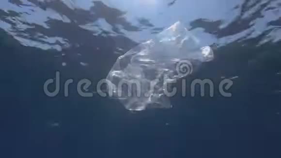 塑料污染水中透明塑料袋废弃的塑料袋慢慢地漂浮在蓝色的水面下视频的预览图