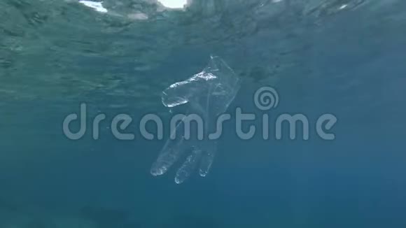 塑料污染废弃的塑料手套在蓝色的水面下慢慢漂流视频的预览图