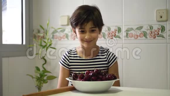 快乐的女孩看着吃着一大碗樱桃视频的预览图