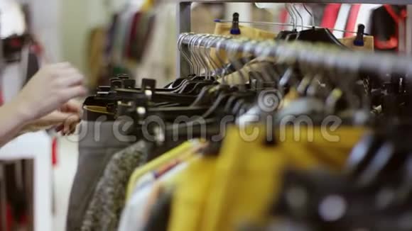一只女性手在服装店的货架上寻找衣服视频的预览图