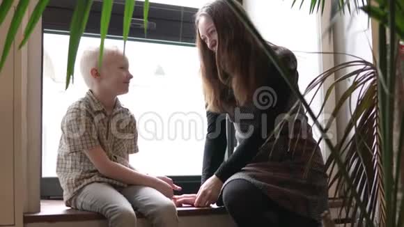 男孩和他的母亲正坐在窗边说话视频的预览图