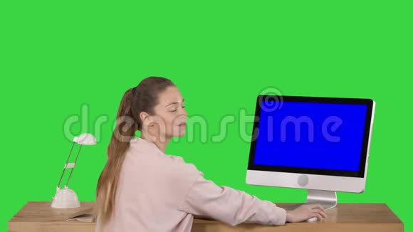 一位开朗的女士坐在桌子旁办公室里有一台电脑她看着摄像机微笑着展示着蓝屏模型视频的预览图