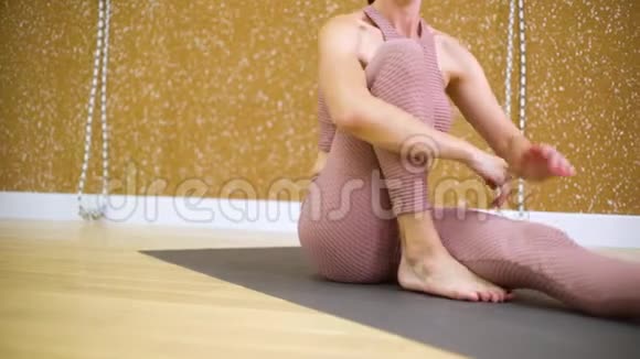 年轻女子坐在垫子上慢动作地在瑜伽工作室伸展身体视频的预览图