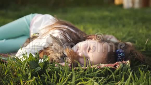 小女孩躺在绿草上拥抱一只棕色的兔子视频的预览图