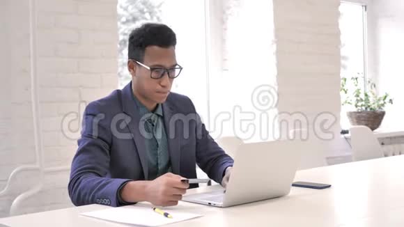 非洲男子通过信用卡在笔记本电脑上购物视频的预览图