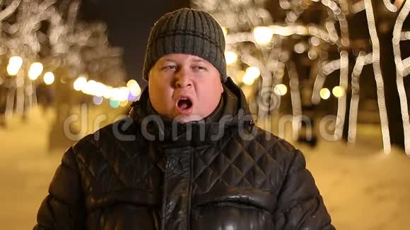 冬天寒冷的夜晚无聊的胖子在户外打哈欠的画像视频的预览图