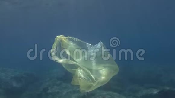 塑料污染蓝色水中黄色塑料袋废弃的塑料袋在阳光下慢慢地漂浮在蓝色的水面下视频的预览图