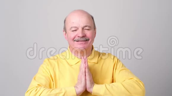 成熟的男人穿着黄色衬衫双手紧握寻求上帝的帮助视频的预览图