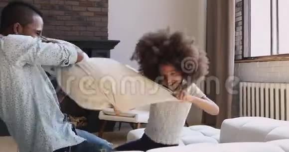 活跃的非洲女儿和爸爸在床上玩枕头大战视频的预览图