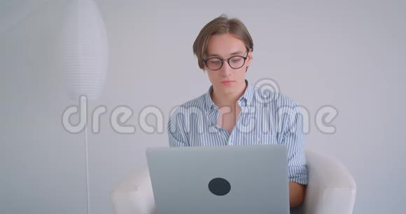 年轻迷人的白种人商人用笔记本电脑看着相机开心地坐在里面的特写镜头视频的预览图