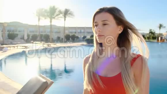在酒店泳池边背景下特写华丽美丽的微笑女孩性感红色比基尼的肖像妇女视频的预览图