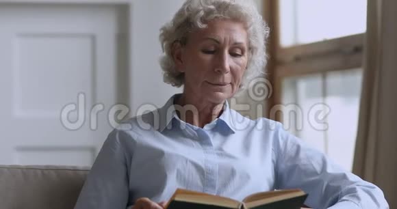 年长的成熟女人在家沙发上放松看书视频的预览图