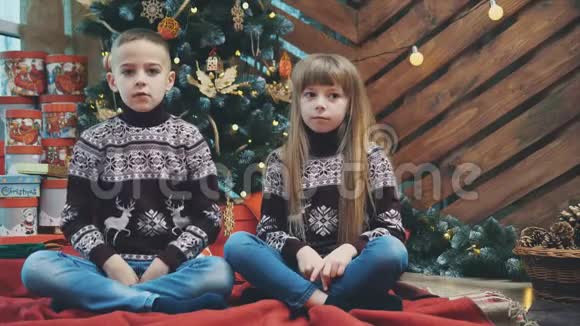 穿着羊毛衫的孩子们在圣诞节的时候用双手竖起大耳朵在木制背景上伸出舌头视频的预览图