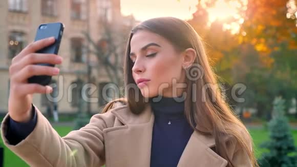 快乐快乐的白种人女孩带着她的手机自拍做滑稽的脸而站在孤立的视频的预览图