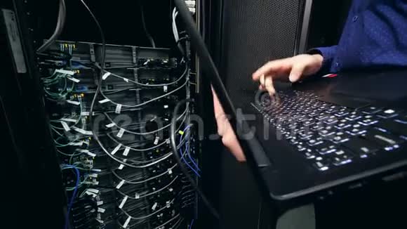 男程序员配合笔记本电脑工作检查数据中心电脑信息技术支助概念视频的预览图