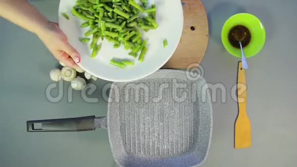 一个女人把新鲜的青豆放进一个沸腾的油锅里视频的预览图