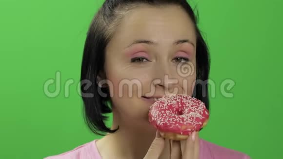 快乐美丽的女孩摆姿势想吃甜甜圈铬键视频的预览图