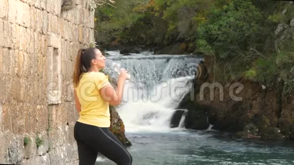 女性饮用水在河边视频的预览图
