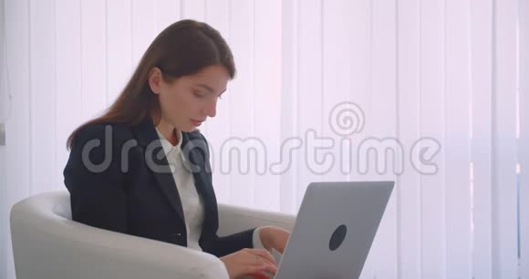 特写侧景照片年轻的高加索女商人用笔记本电脑看着镜头开心地坐着微笑视频的预览图
