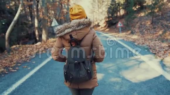 秋天背着背包的女孩走在乡间小路上视频的预览图