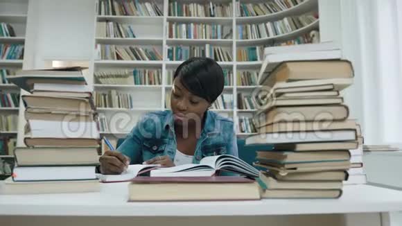 非洲女学生在学习在现代图书馆的书周围做一些笔记视频的预览图