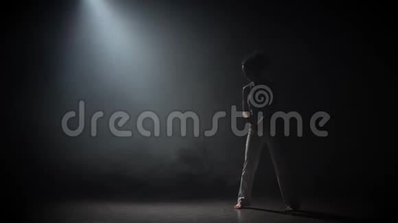 卷曲少女在黑暗中练习卡波伊拉在演播室的聚光灯下视频的预览图