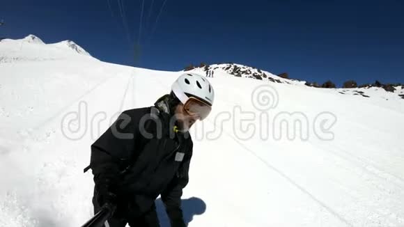 阳光明媚的一天一个自拍的宽角男滑雪者穿着黑色装备和白色头盔骑在雪坡上这就是视频的预览图