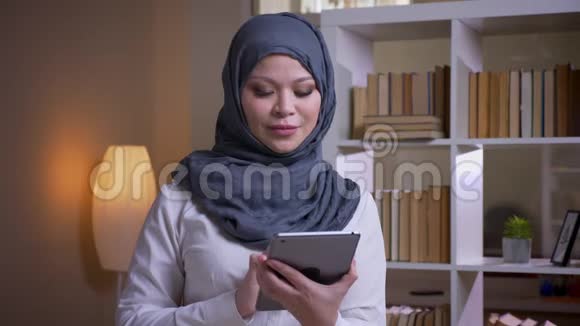 成年穆斯林女商人的特写镜头用显示绿色屏幕的平板电脑拍摄同时开心地微笑着视频的预览图