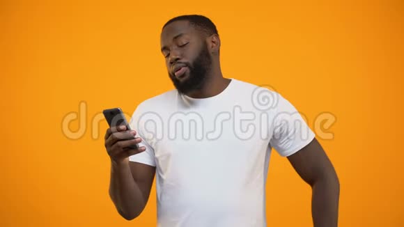 兴奋的美国黑人男子持有智能手机和美元在线汇款视频的预览图