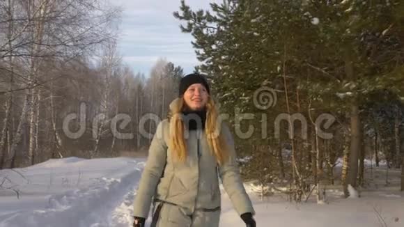 年轻漂亮的白种人女孩穿着夹克在雪天的冬天森林里散步和跳跃玩耍视频的预览图