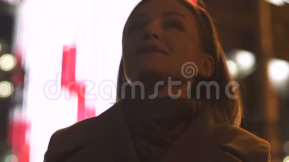 充满灵感的女人站在明亮的广告牌背景下享受城市的夜晚视频的预览图