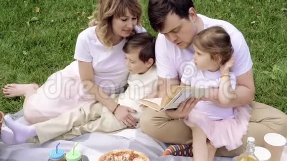 快乐的家庭和孩子们在户外野餐上读一本书视频的预览图