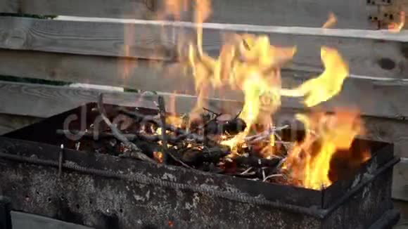 明亮的橙色火焰燃烧在黑色金属烤架特写视频的预览图