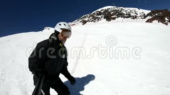 阳光明媚的一天一个自拍的宽角男滑雪者穿着黑色装备和白色头盔骑在雪坡上这就是视频的预览图