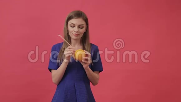 一个美丽的女孩穿着一件连着耳机和一个橘子然后跳舞和听音乐紫色工作室视频的预览图