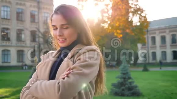 美丽的白种人女人看着镜头冷着脸站着在阳光下快乐地微笑城市背景视频的预览图
