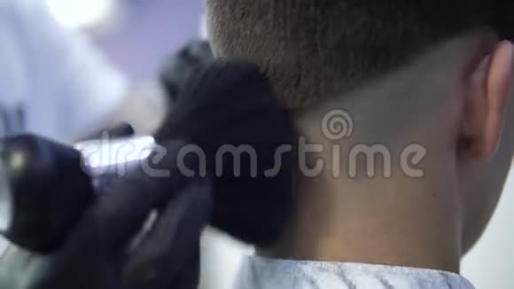 男理发师在沙龙为年轻客户使用滑石粉视频的预览图
