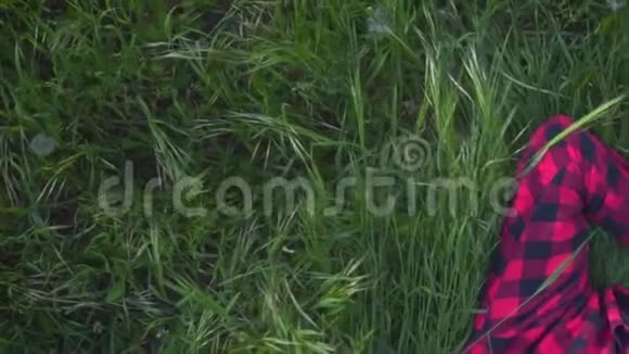 女孩躺在草坪上休息在阳光明媚的一天在公园的草地上穿着红黑衬衫的草地上的女人视频的预览图