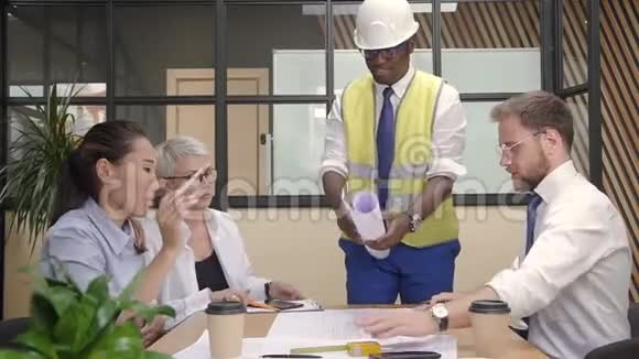 非洲建设者展示蓝图的多种族团队在临时办公室视频的预览图