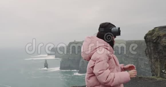 有魅力的年轻女子在悬崖顶部使用VR她非常印象深刻笑得很大特写镜头视频的预览图