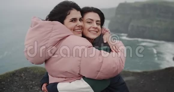 漂亮的两位女士在惊人的悬崖屋顶的镜头前互相拥抱展示了一个大的视频的预览图