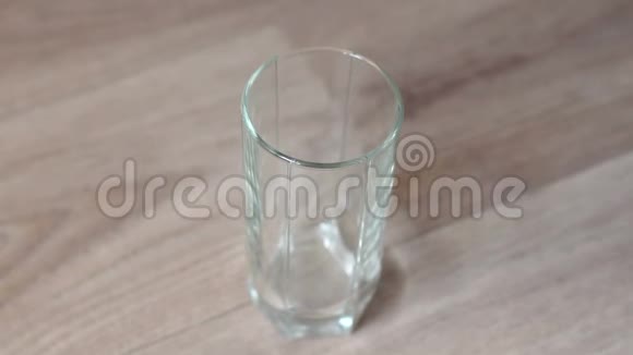 一个女人把水倒进木桌上的玻璃里的特写镜头慢动作视频的预览图