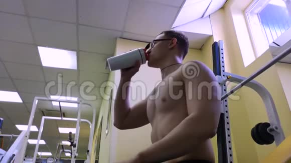 年轻人在健身房里坐在训练台上喝水视频的预览图