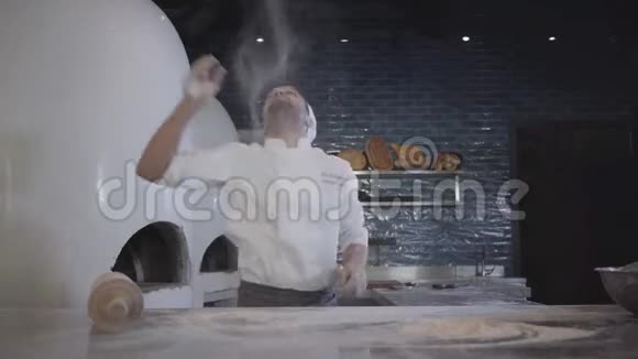厨师穿着白色制服快速工作把面团抛起来用大木擀面杖在桌子上滚动视频的预览图