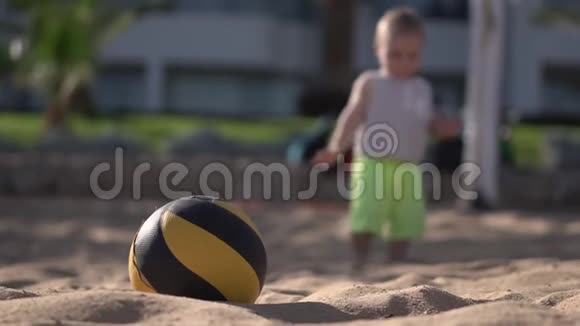 小男孩走在海滩上的山谷球附近视频的预览图