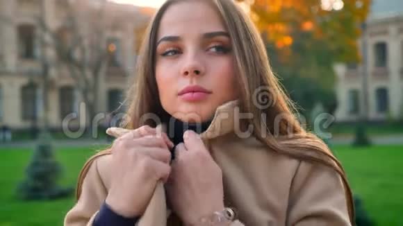 可爱的黑发白种人女孩躲在她的外套而站在外面的城市视野和目光视频的预览图