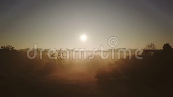 美丽的金色雾晨房子和村庄黎明的光线飞翔的鸟录像片段背光空中飞行农村视频的预览图
