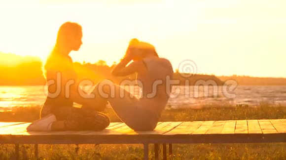 两个年轻漂亮的女孩在日出或日落前在海边的沙滩上脱衣服视频的预览图