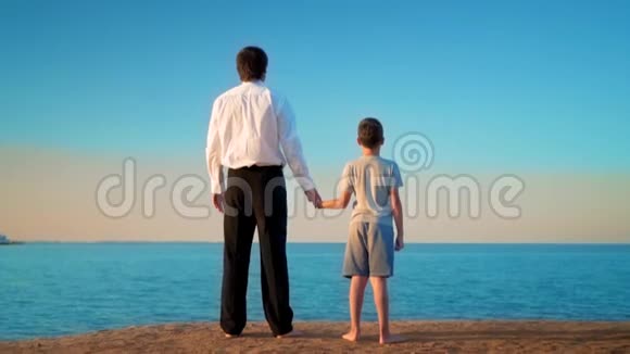 父亲和儿子站在海边的手旁父亲用手指指着远处视频的预览图