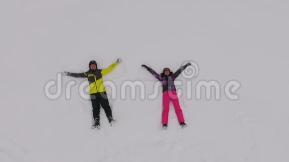 两个快乐的滑雪者躺在雪地上在布科维尔做波浪运动视频的预览图